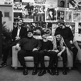 a black and white photo of 5 guys in a couch